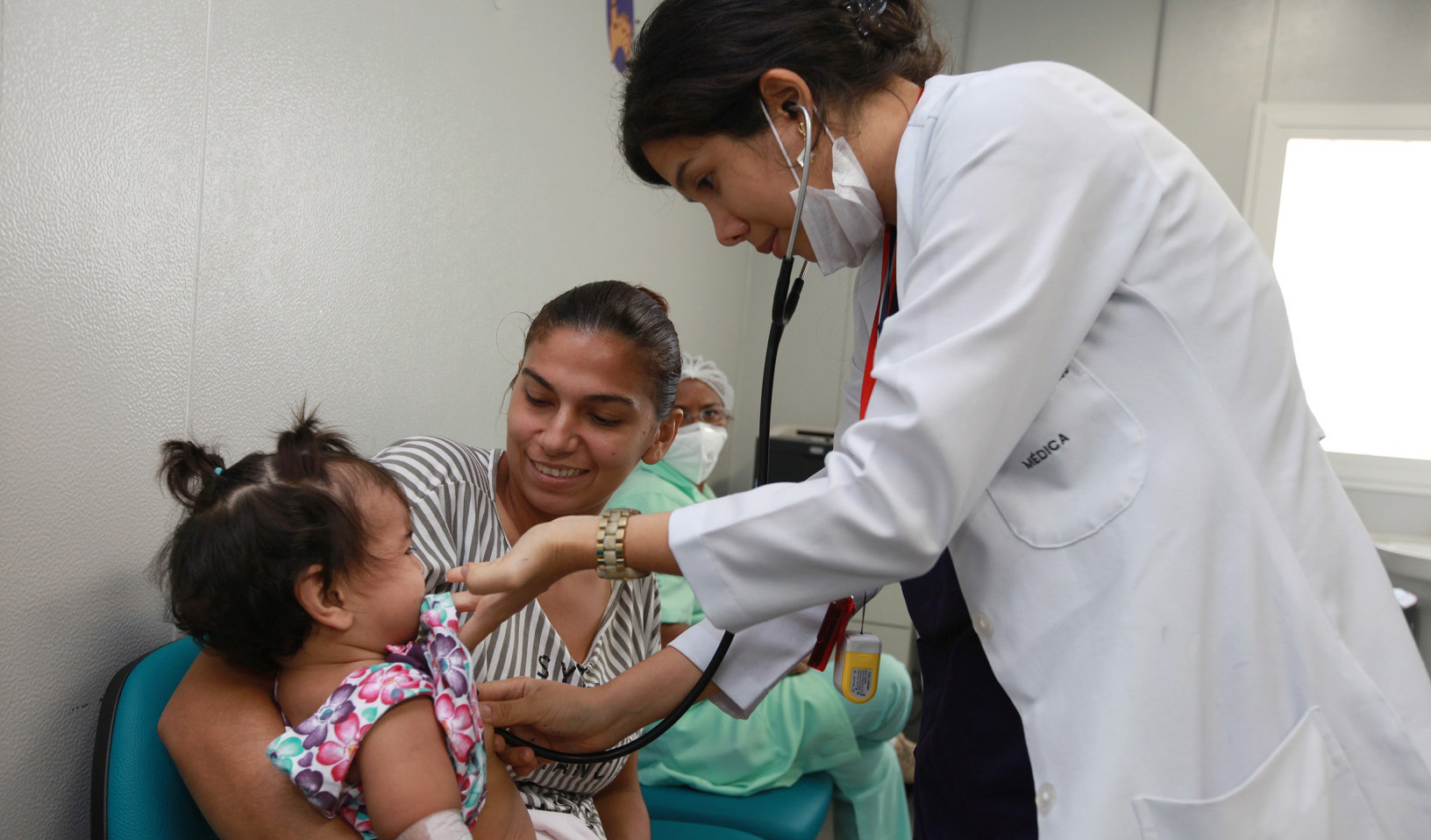 médica atendendo um bebê qu está no colo da mãe